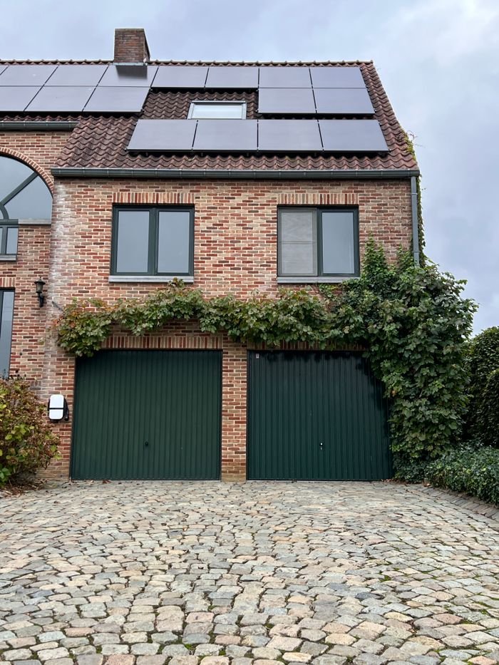 services-01 Charming brick house with solar panels and ivy-covered garage. Eco-friendly architecture.