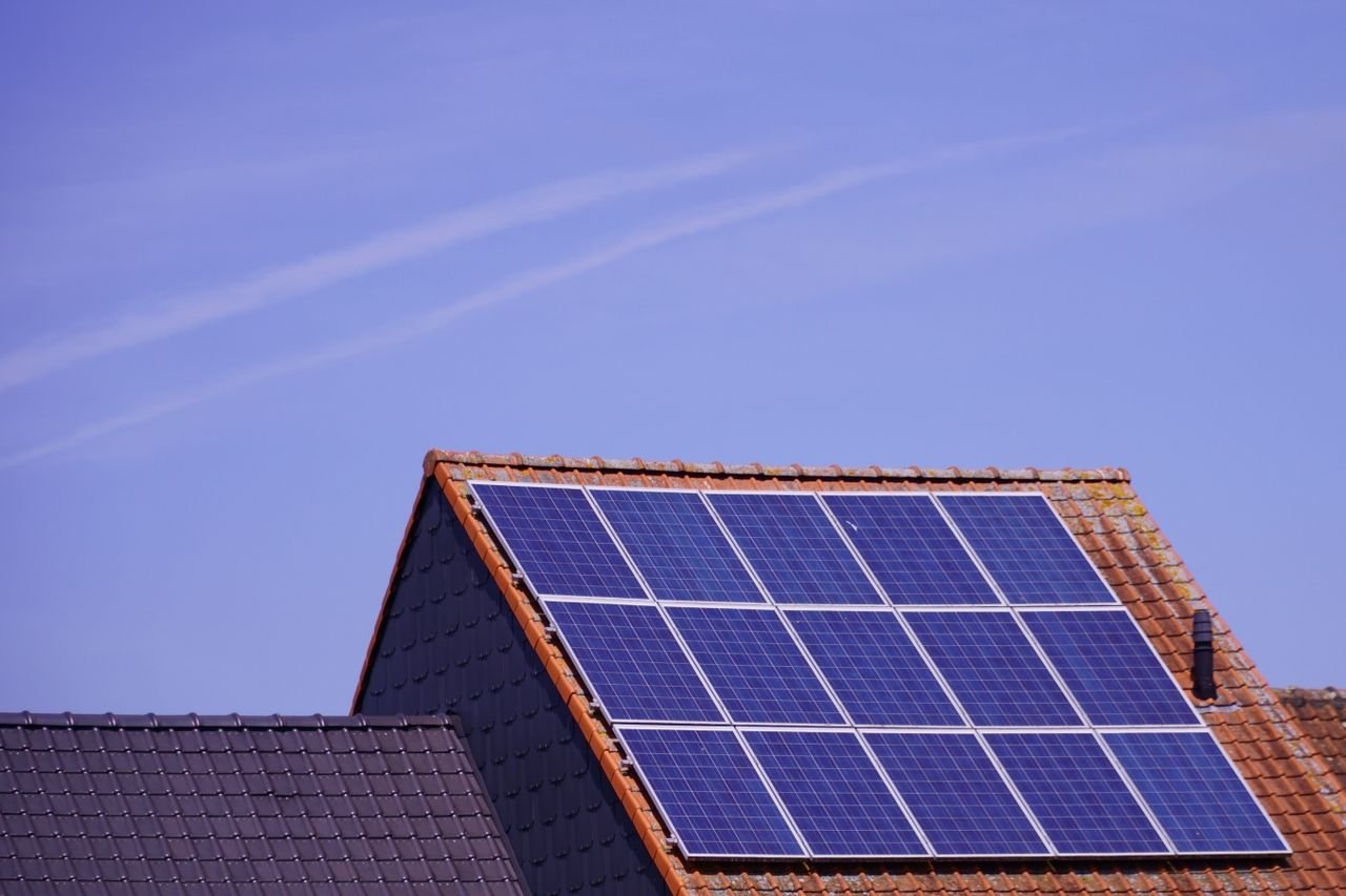 services-01 Close-up of solar panels on a tiled rooftop under a clear sky, showcasing renewable energy.