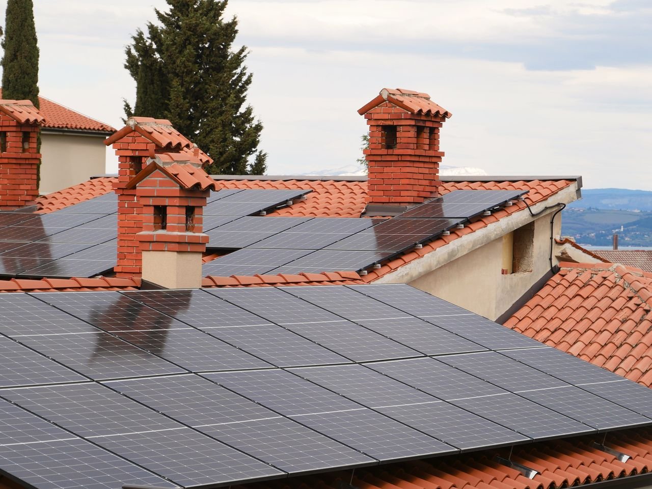 Mastering the First Impression: Your intriguing post title goes here Solar panels on tiled roofs of houses with chimneys, capturing clean energy.